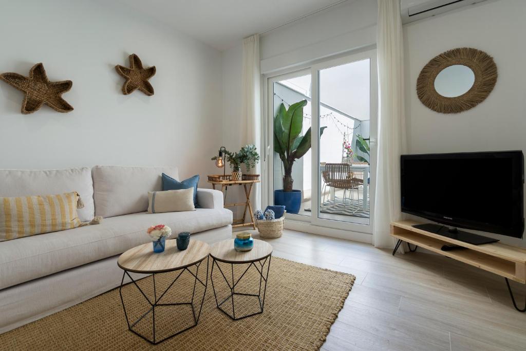 uma sala de estar com um sofá e uma televisão de ecrã plano em Mistral playa la caleta Ascensor Grupo AC Gestion em Cádiz