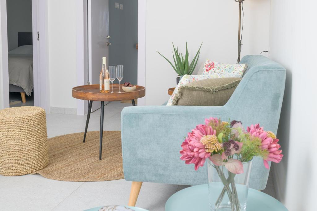 a living room with a blue chair and a vase with flowers at PRINCES of the Dead Sea by CROWN in Neve Zohar