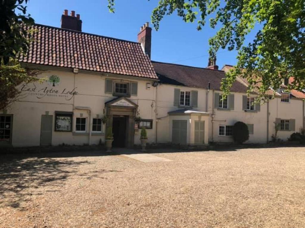 a large white house with a driveway in front of it at East Ayton Lodge Hotel, Scarborough in Scarborough