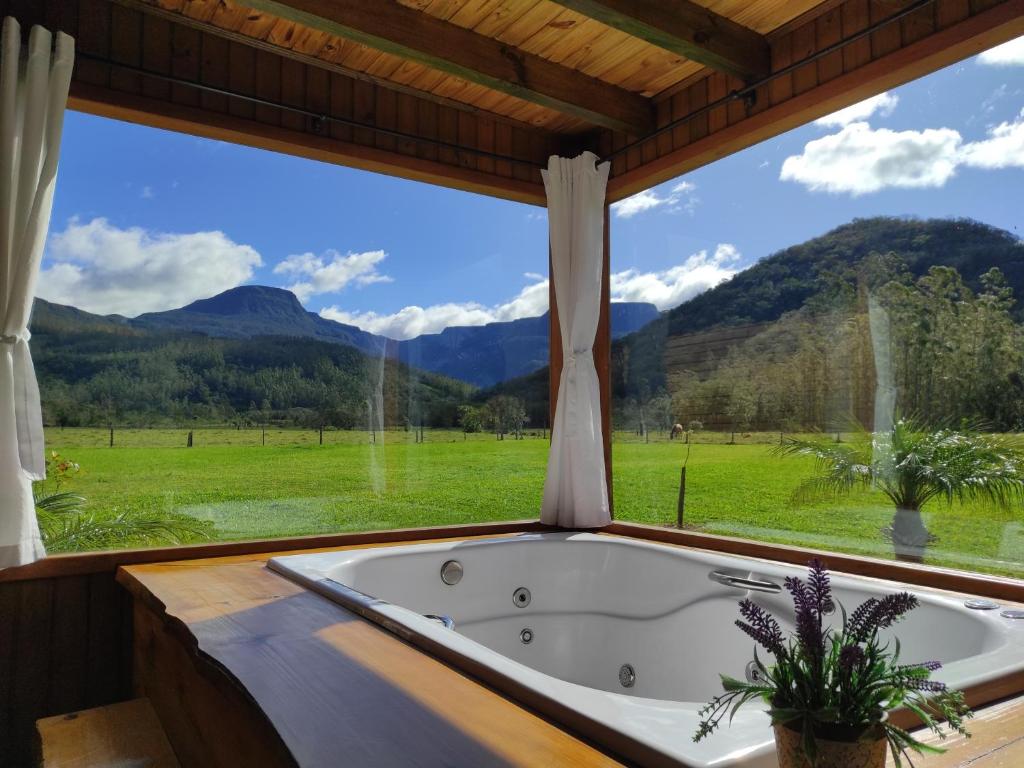 a bath tub in a room with a large window at Pousada Canyons do Sul in Praia Grande