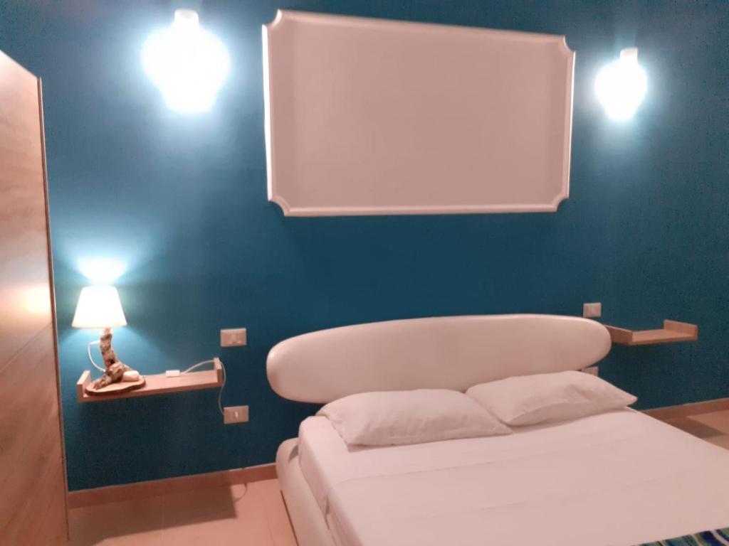 1 dormitorio con cama blanca y pared azul en Casa Amy en San Michele Salentino