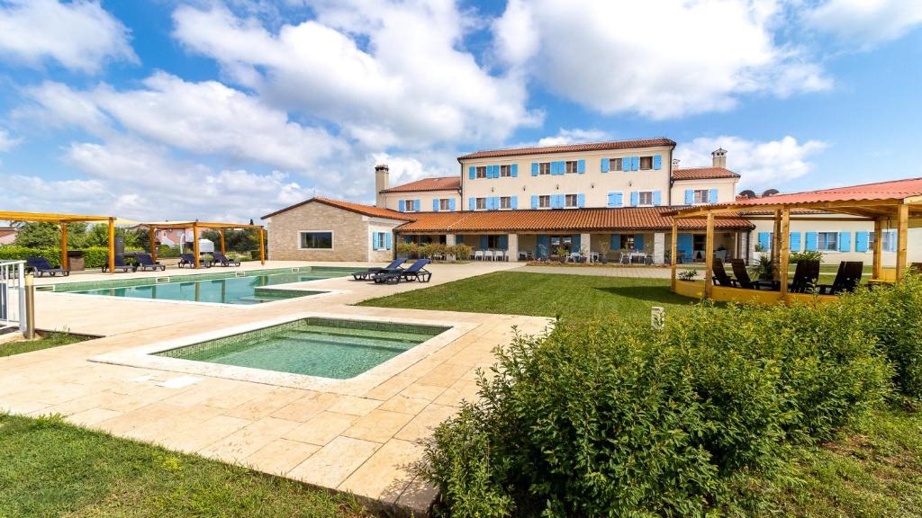 ein großes Haus mit Pool im Hof in der Unterkunft VELANERA Hotel & Restaurant in Medulin