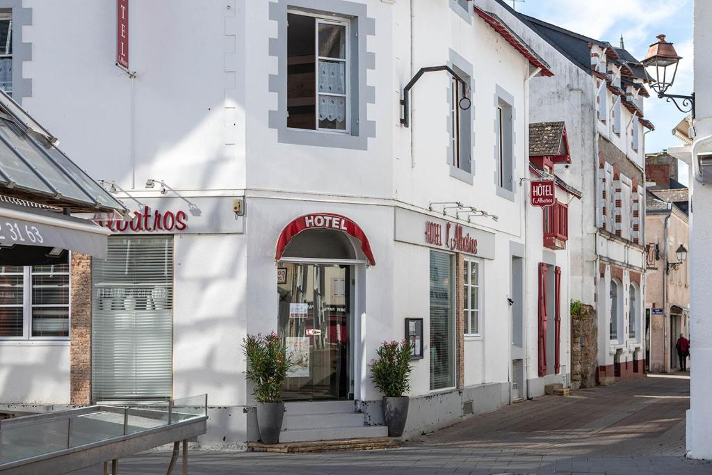 een wit gebouw met een veertiger winkel in een straat bij Hôtel L'albatros in Le Pouliguen