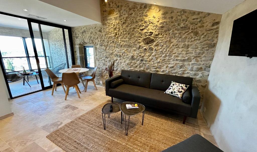 salon z czarną kanapą i kamienną ścianą w obiekcie Le Donjon de Lily - Cœur de La Cité Médiévale w Carcassonne