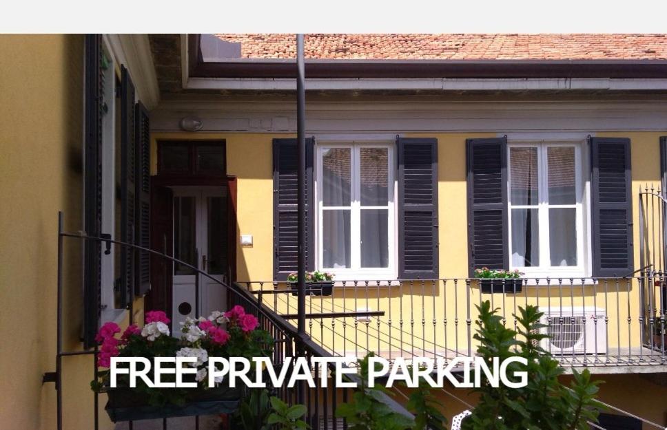 a yellow house with black shuttered windows and flowers at Beautiful bohemian apartment in center conditioned air in Como