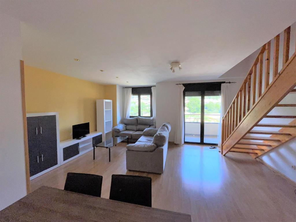 a living room with a couch and a tv and stairs at Duplex tres habitaciones Pirineo in Boltaña