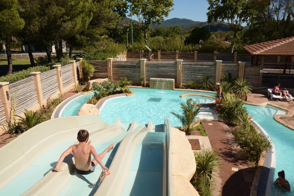 un hombre bajando por un tobogán en una piscina en Camping La Prairie, en Le Muy