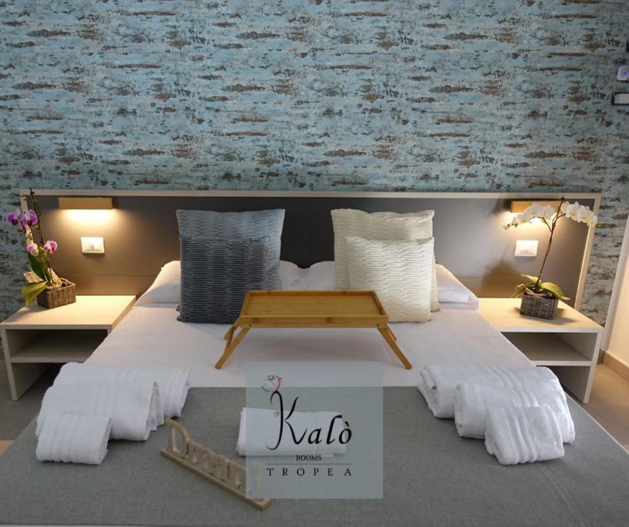 a bedroom with a large bed with a table on it at KALÓ ROOMS in Tropea