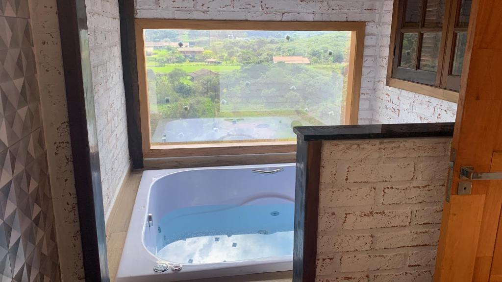 eine Badewanne im Bad mit Fenster in der Unterkunft chalés Roma in Santo Antônio do Pinhal