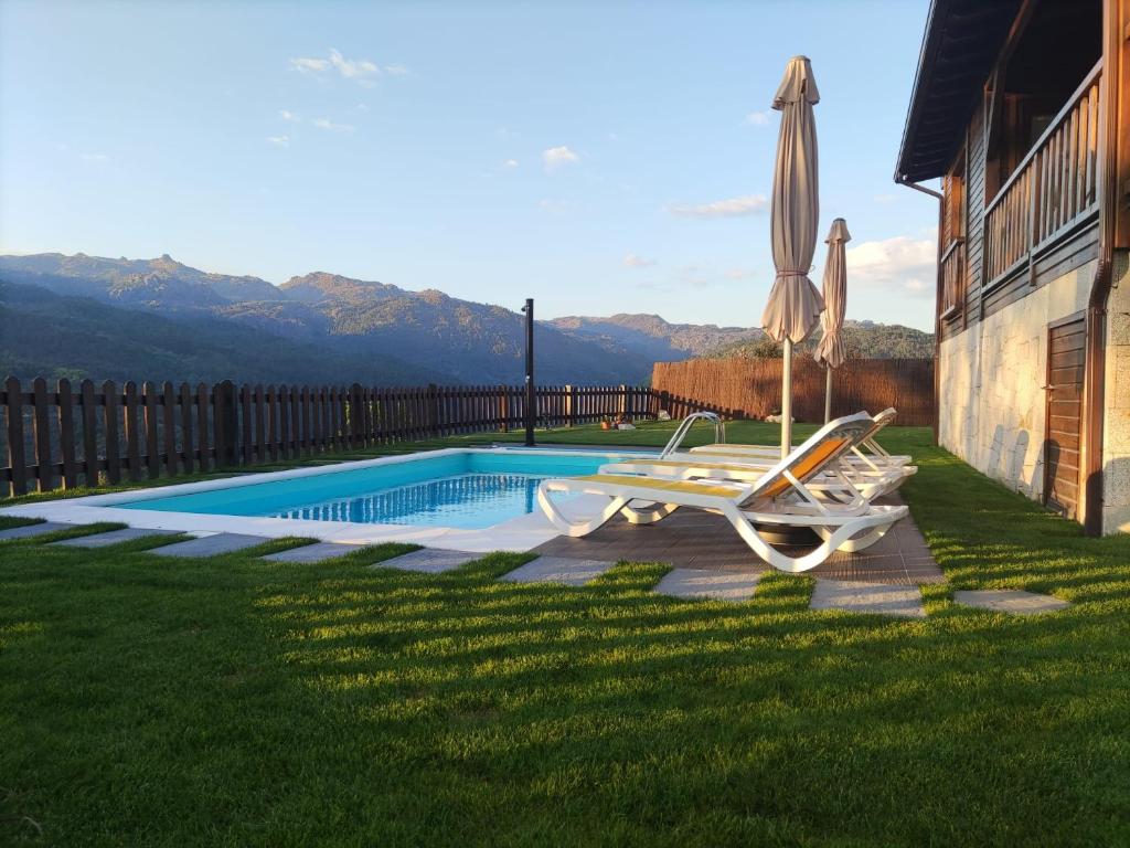 - une piscine avec 2 chaises longues et un parasol dans l'établissement Quinta da Resteva-Chalé do RIBEIRO, à Vieira do Minho