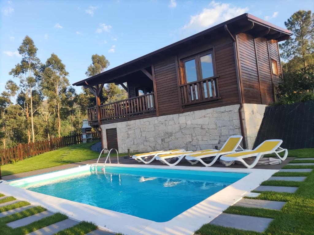 une maison avec une piscine en face d'une maison dans l'établissement Quinta da Resteva-Chalé do RIO, à Vieira do Minho