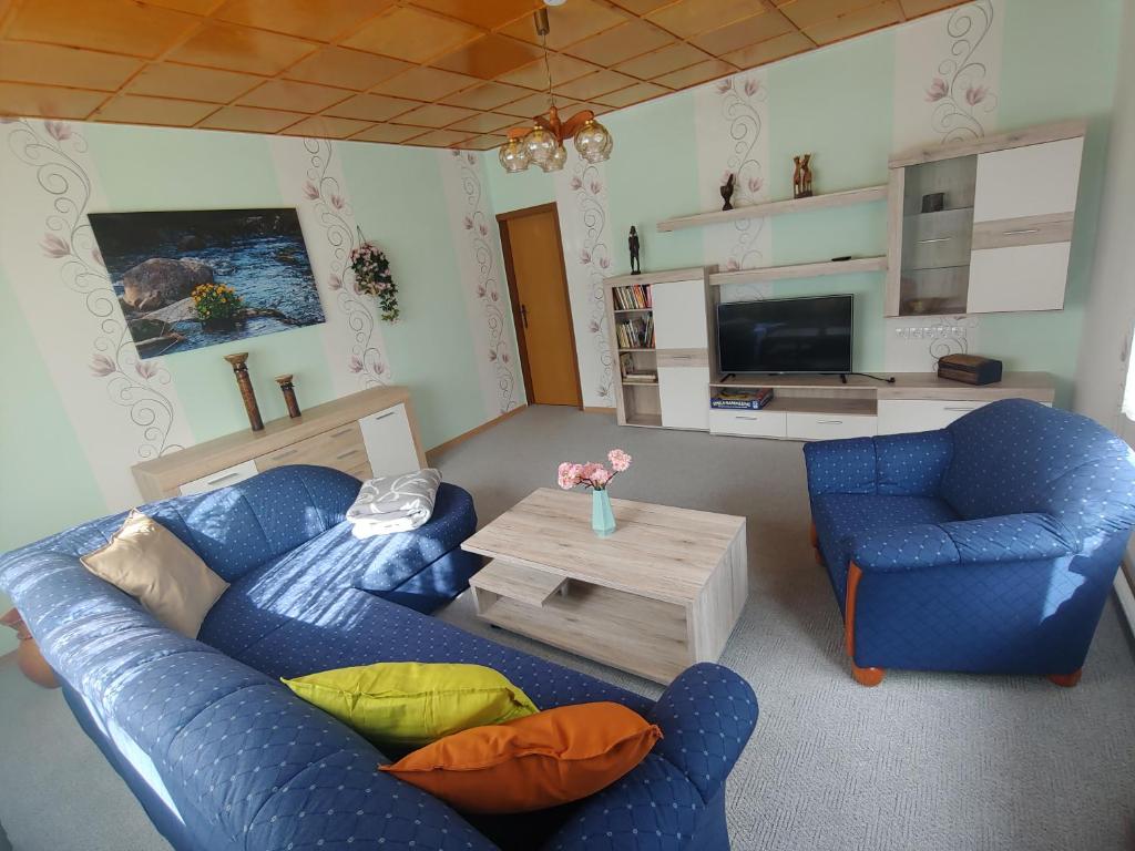 a living room with two blue chairs and a table at Gemütliche Ferienwohnung in Körba am See 