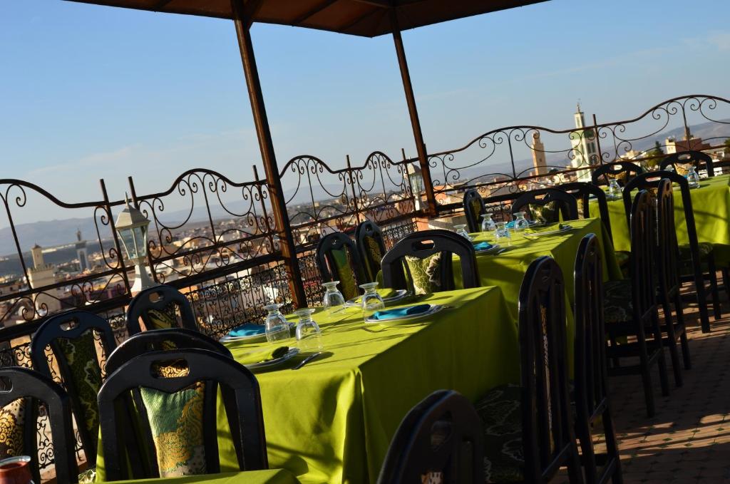 eine Reihe von Tischen mit grünen Tischdecken auf dem Balkon in der Unterkunft Riad Selma in Meknès