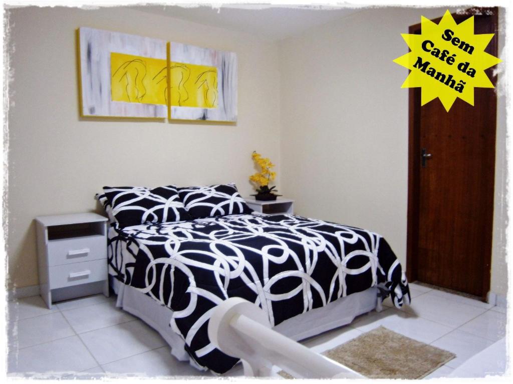 um quarto com uma cama com um edredão preto e branco em Suítes de Setiba - HOSPEDARIA OCA RUCA em Guarapari