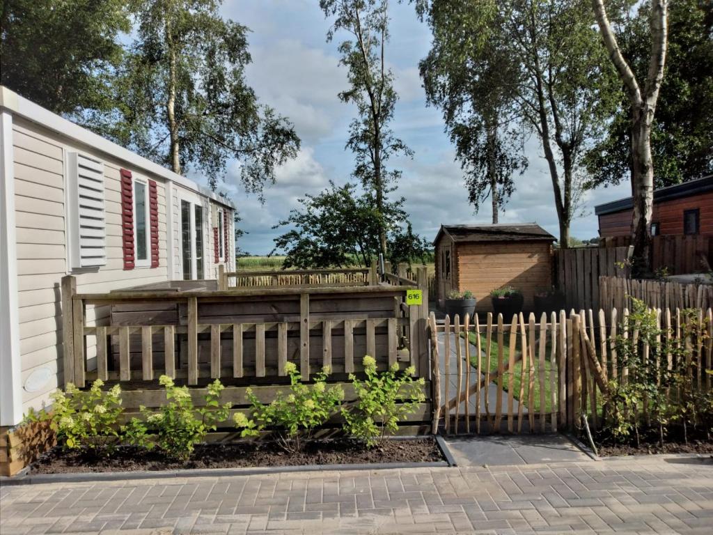 a wooden fence next to a white house at Chalet Berg 616 op vakantiepark Bergumermeer aan het water in Suameer