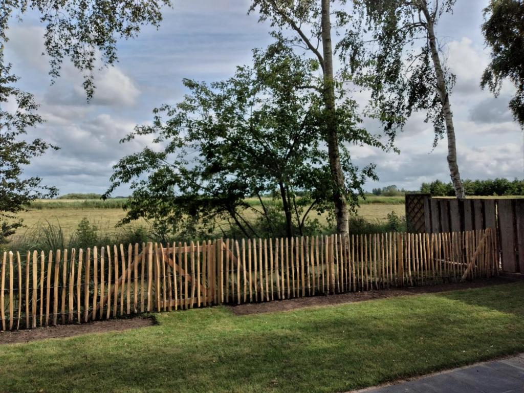 a wooden fence with a field behind it at Chalet Berg 616 op vakantiepark Bergumermeer aan het water in Suameer