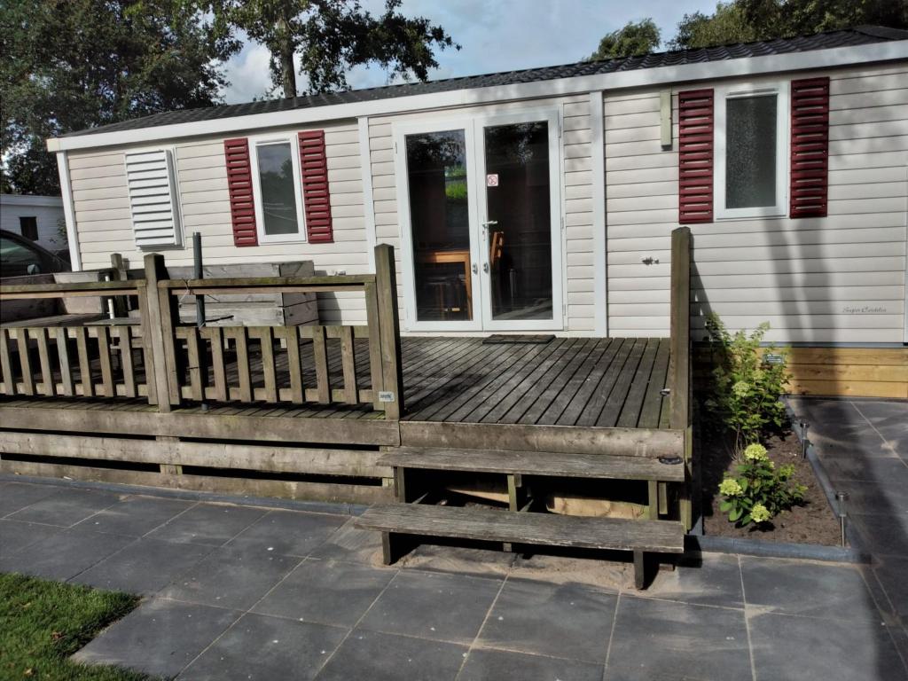 a large wooden deck in front of a tiny house at Chalet Berg 616 op vakantiepark Bergumermeer aan het water in Suameer