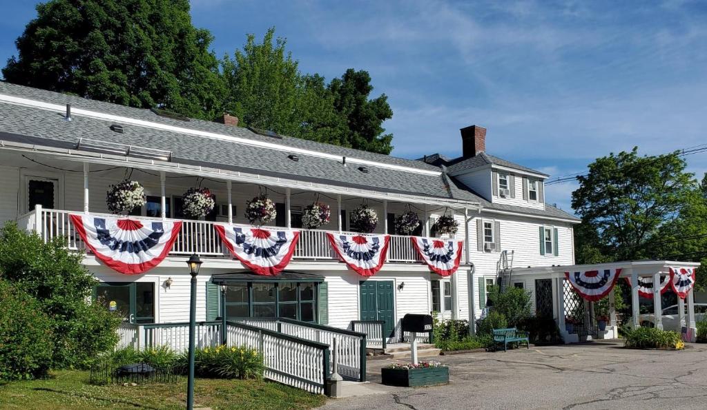 a white house with american flags hanging from it at Windrifter Resort in Wolfeboro