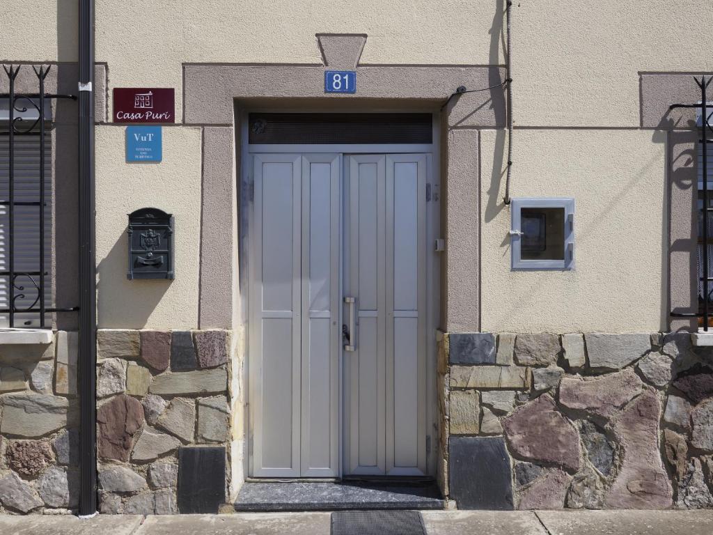 una puerta blanca en un edificio con una pared de piedra en CASA PURI - ACOGEDORA CASA CON PARKING y PATIO INTERIOR, 