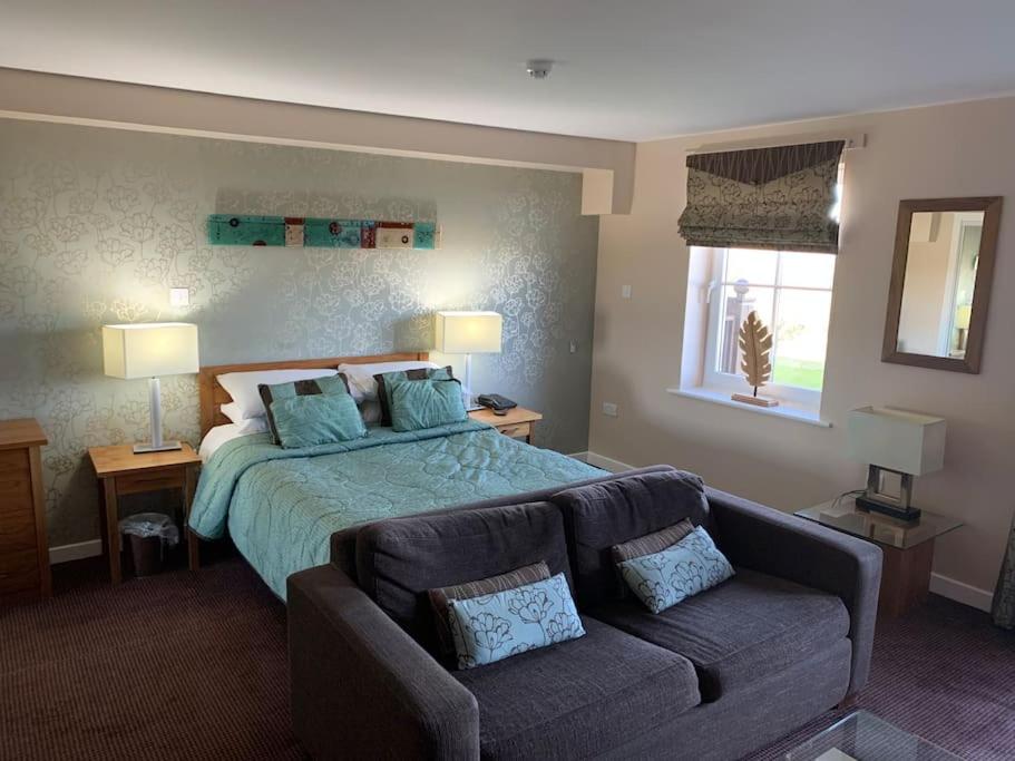 a large bedroom with a bed and a couch at Ullswater Suite in Penrith