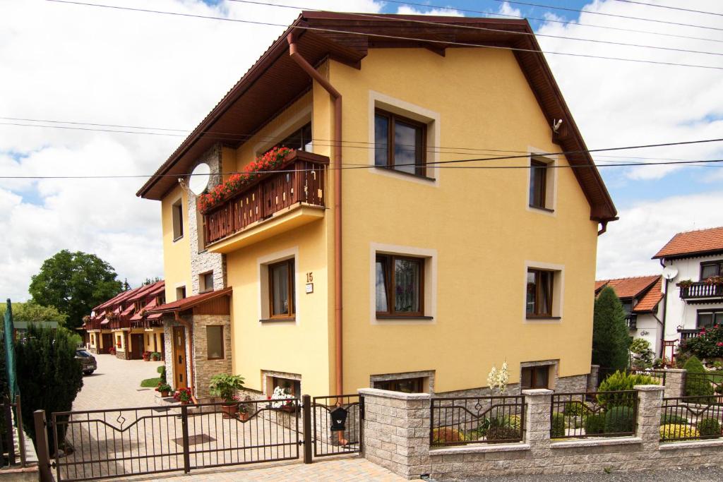 żółty dom z balkonem na ulicy w obiekcie Apartmány Ďurik w Liptowskim Mikulaszu