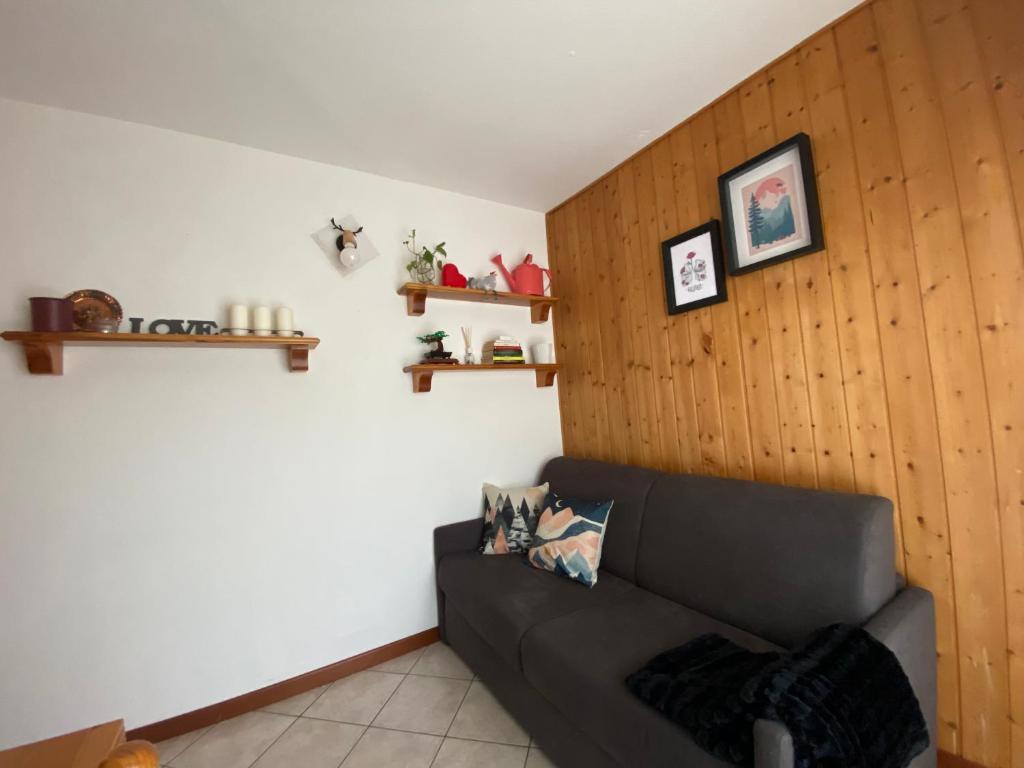 a living room with a black couch and wooden wall at Piacevole appartamento ideale per relax e sport in Sella della Turra