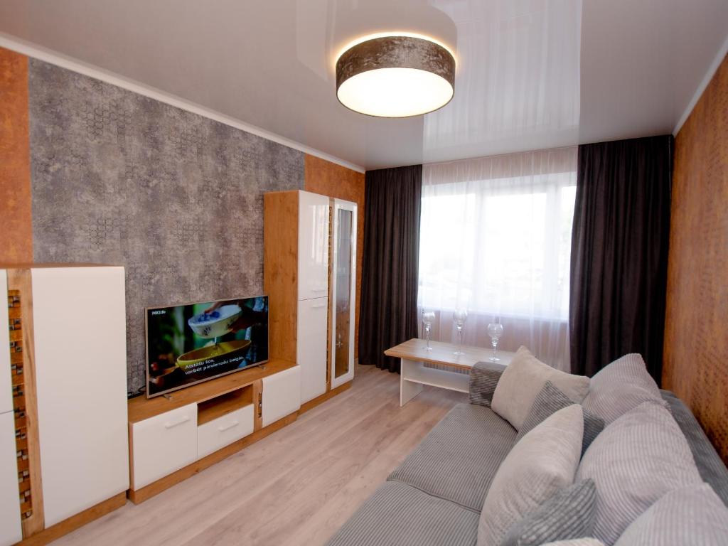 a living room with a couch and a flat screen tv at Jūras 4 Apartament in Ventspils