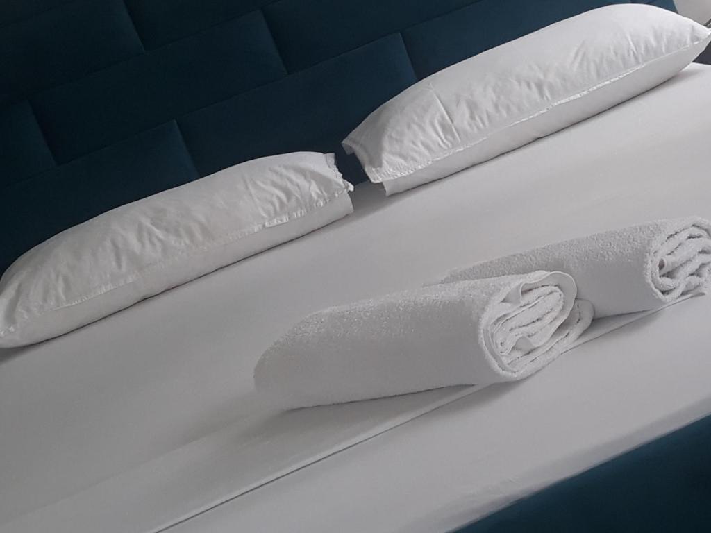 2 rotoli di cuscini bianchi su un letto di Isabel's B&B a Tirana