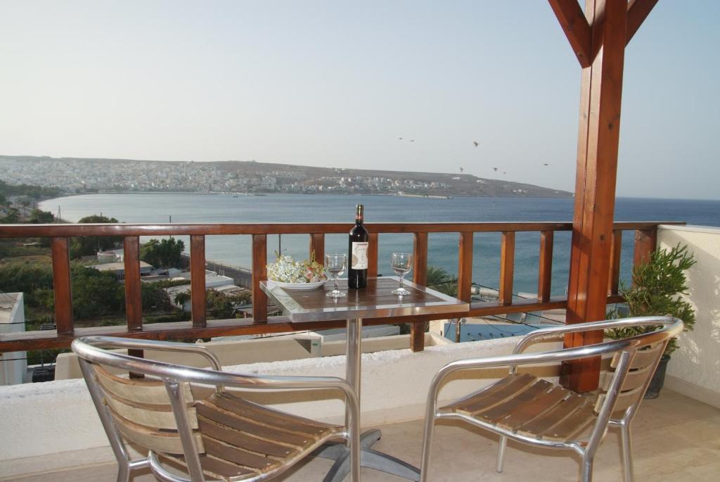 a table and chairs on a balcony with a bottle of wine at Bay View Apartments in Sitia