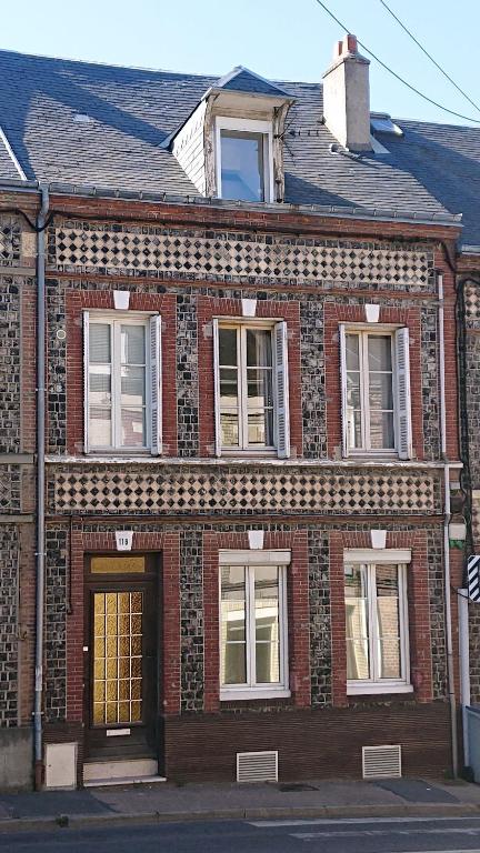 an old brick building with windows on a street at Tout un 2eme étage à 300 mètres de la mer, chez l'habitant ! in Fécamp