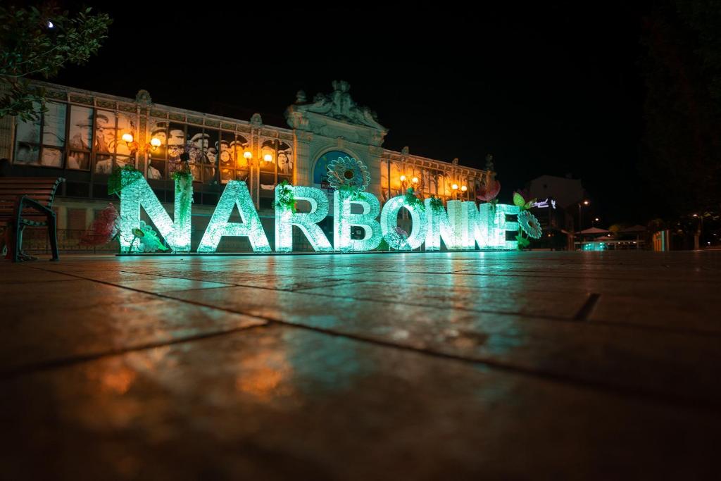 a large sign in front of a building at night at Superbe appartement à 2 pas des Halles, Climatisé, terrasse, garage in Narbonne