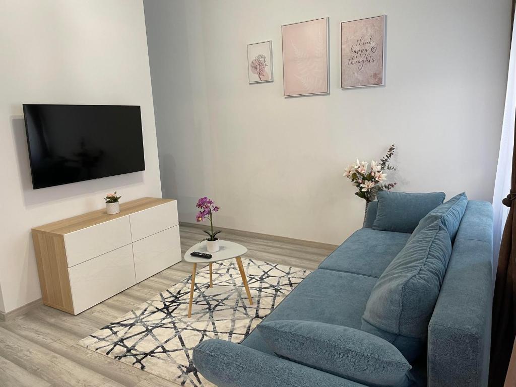 uma sala de estar com um sofá azul e uma televisão em Eden City Home em Gyor