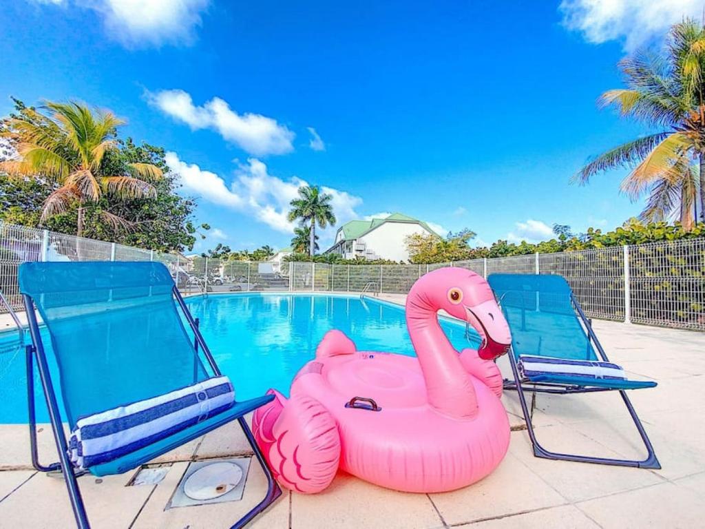 two chairs and a pink inflatable flamingo next to a swimming pool at Kalina, beautiful duplex 100m from Orient Bay beach with swimming pool in Orient Bay