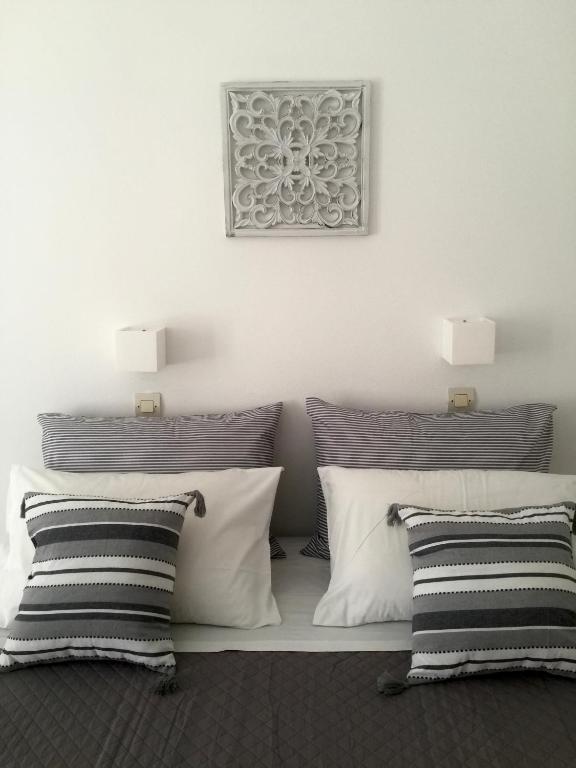 Cama blanca con almohadas blancas y negras en Rodia Studios &amp; Apartments, en Parikia