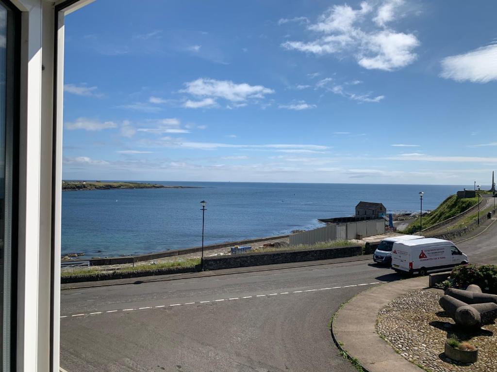 a road with a view of the ocean from a window at Traditional Caithness Stone house in Wick