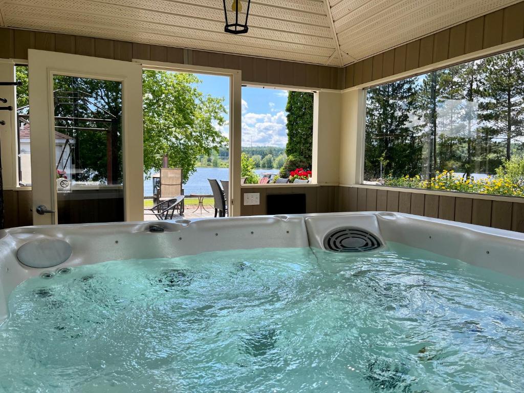 a jacuzzi tub in a room with windows at Auberge l'Intermède du lac in Disraeli