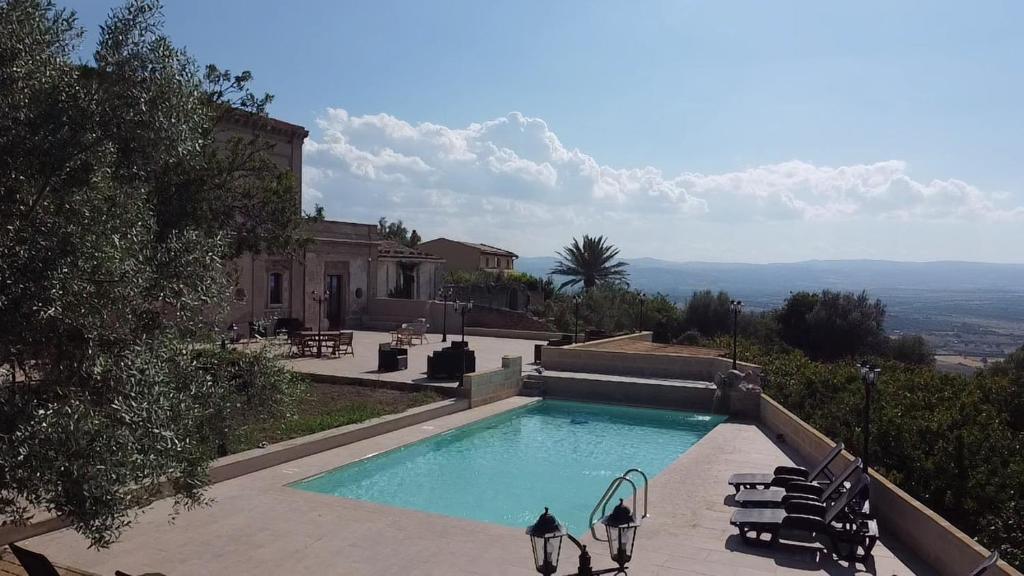 uma piscina com cadeiras e uma casa em Casale Ciricó tra Catania e Siracusa em Carlentini