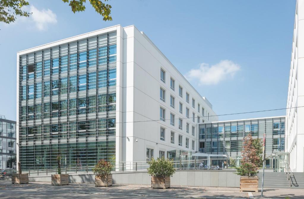 un grand immeuble de bureaux blanc avec des plantes en pot devant lui dans l'établissement Hotel Lyon-ouest, à Lyon