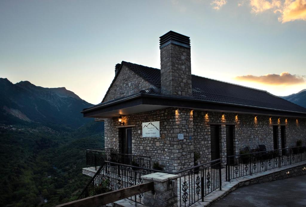 Casa de piedra con balcón con vistas a las montañas de fondo en Δωμάτια με θέα, en Méga Khoríon