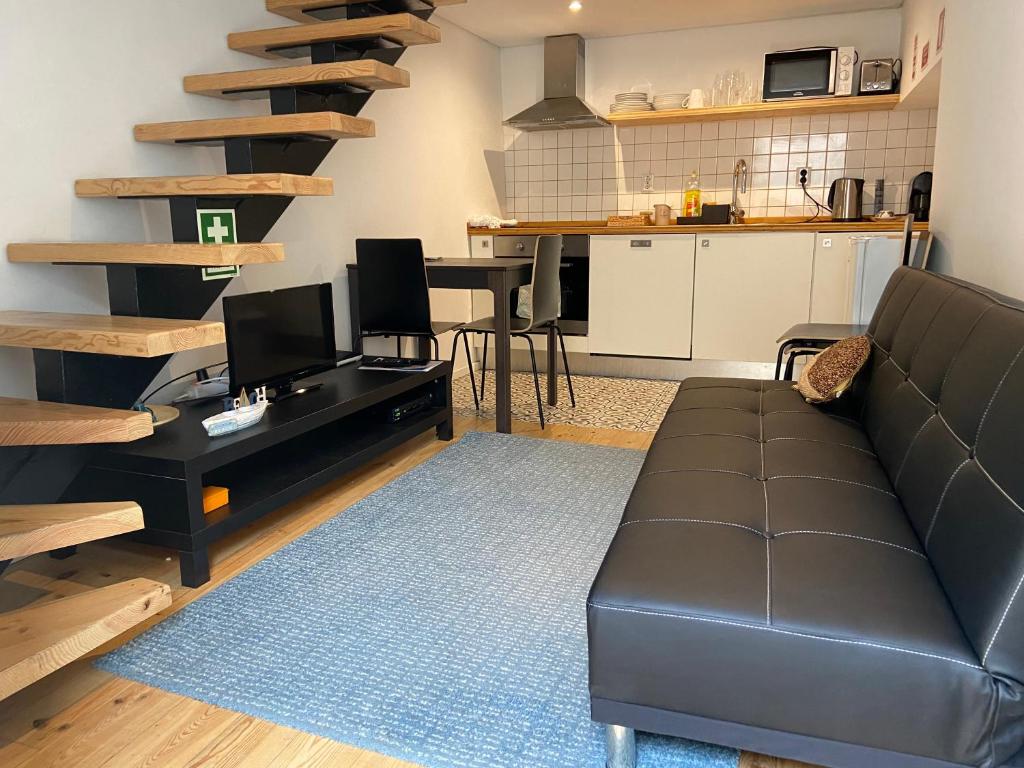 a living room with a black couch and a kitchen at Cassiopeia Duplex in Setúbal