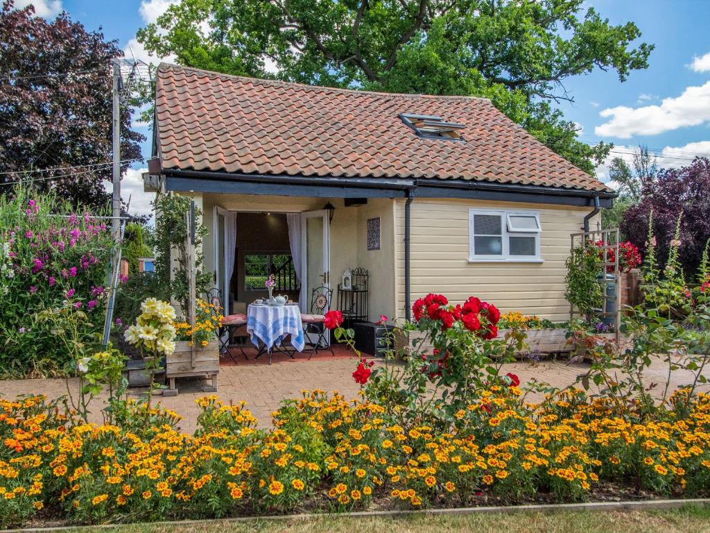 ein kleines Haus mit einem Tisch und Blumen in der Unterkunft Norbank Cottage in Bressingham