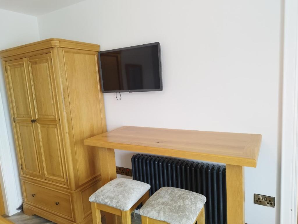 a room with a desk with a tv and two stools at Biddy Ban’s in Carnmalin