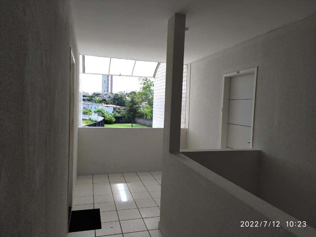 a white hallway with a mirror and a window at APARTAMENTO 2 QUARTOS MOBILIADO - GARANHUNS - PE in Garanhuns