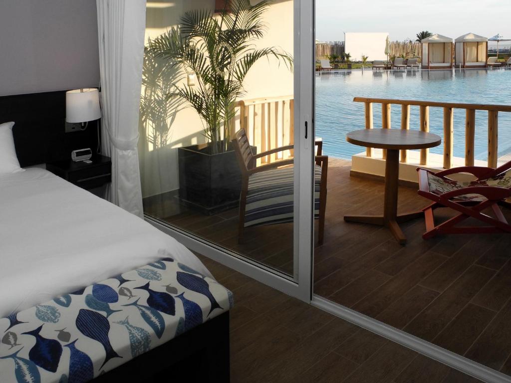 a bedroom with a bed and a balcony with a view of the water at Aranwa Paracas Resort & Spa in Paracas