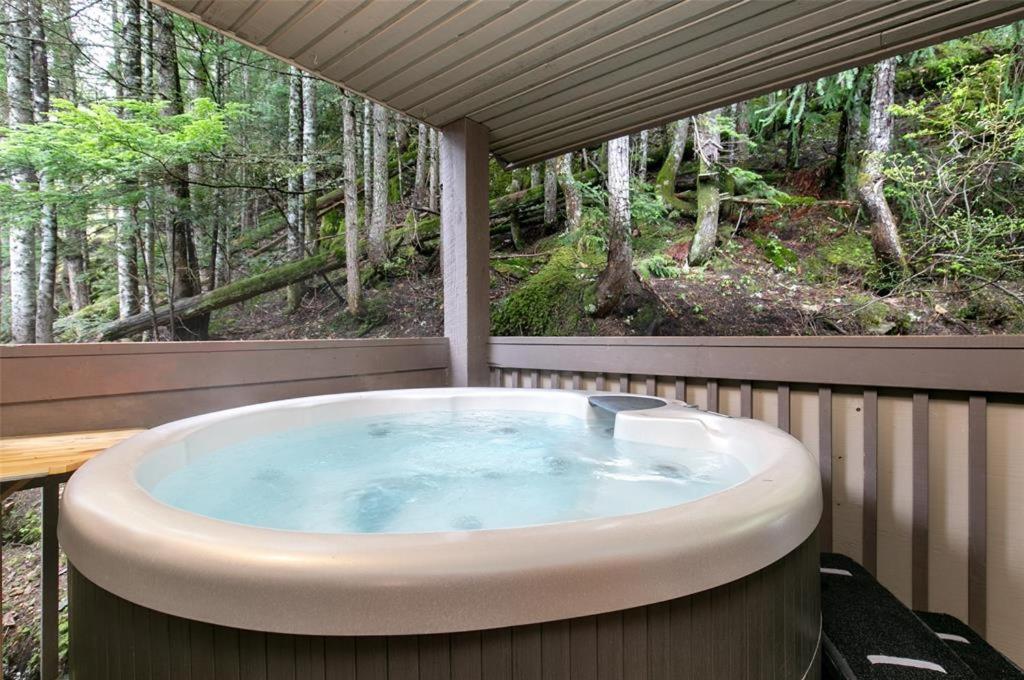 a hot tub on a deck with a view of the woods at Ski In Ski Out 3BR Townhome in Creekside by Harmony Whistler in Whistler