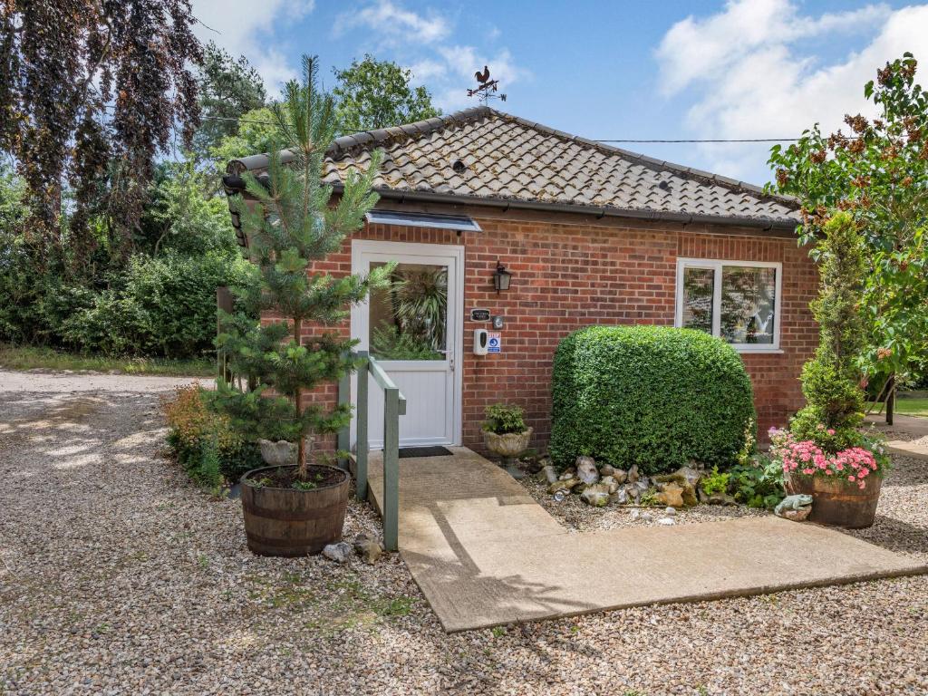 a small red brick house with a white door at The Lodge in Coltishall