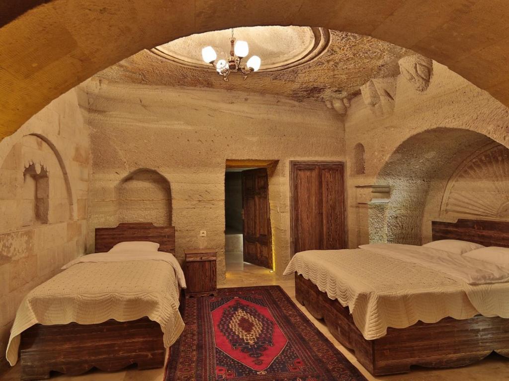 a bedroom with two beds in a stone room at Family Cave Suite Hotel in Göreme