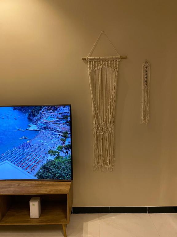 a flat screen tv sitting on a stand next to a curtain at Bohemian style in Abha