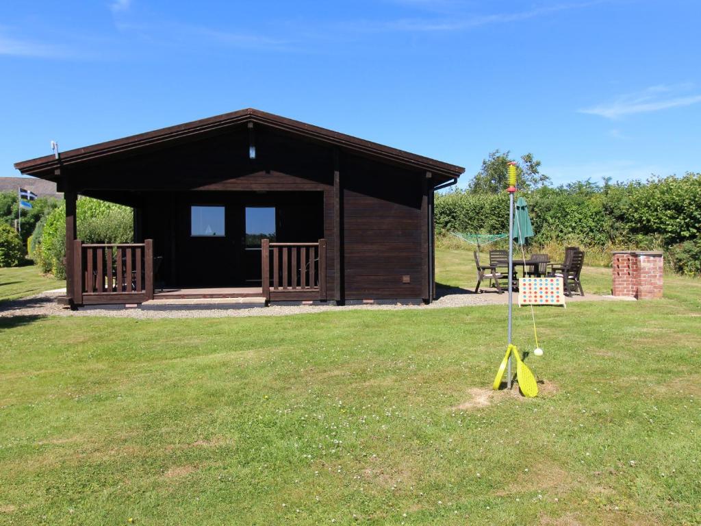 a small cabin with a sign in the grass at Maple Lodge in Bodmin