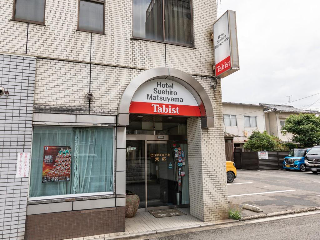 uma loja com uma placa na frente de um edifício em Tabist Business Hotel Suehiro Matsuyama em Matsuyama